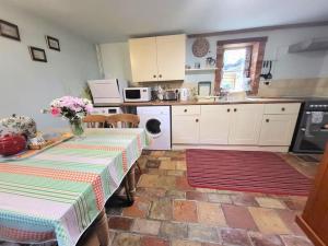 uma cozinha com duas mesas e uma cozinha com armários brancos em The Old Dairy in rural sea side location em Norwich