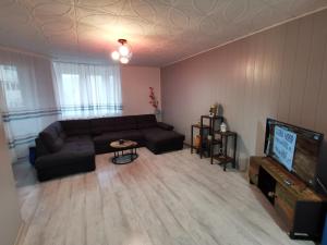 a living room with a black couch and a television at Noah Apartment in Uricani