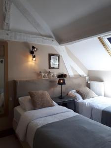 een slaapkamer met 2 bedden op een zolder bij La Perle Secrète in Theneuille