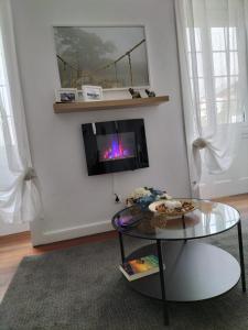 a living room with a table and a tv on a wall at Alojamento Pestana in Horta