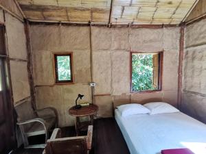 a bedroom with a bed and a table and two windows at Harvest Moon Valley in Ban Pang Luang