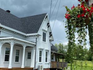 a white house with a flower basket of red roses at Magnifique centenaire rénovée, air climatisé, arcade, 3 chambres fermées in Austin