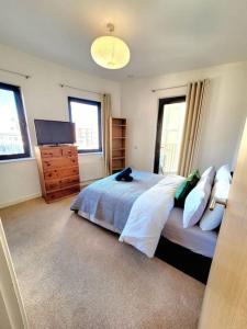 1 dormitorio con 1 cama, TV y ventanas en Battersea Power Station Suite, en Londres