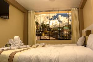 een slaapkamer met een bed en een groot raam bij Kaaro Hotel Puno in Puno
