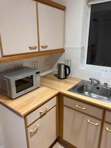 uma cozinha com um micro-ondas e um lavatório em Beautiful 1 bed bungalow em Ryde
