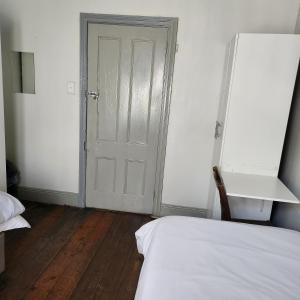 1 dormitorio con cama y puerta blanca en Msunduzi River View backpackers, en Pietermaritzburg