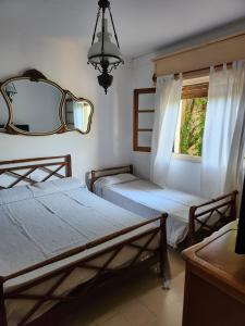 1 dormitorio con 2 camas, espejo y ventana en Deptos Medusas en Pinamar