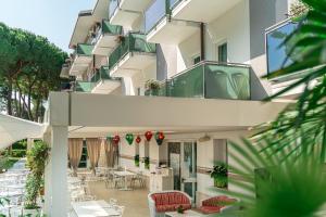 a building with a balcony with chairs and tables at Hotel Mediterraneo in Lignano Sabbiadoro