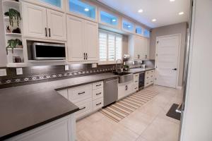 a large kitchen with white cabinets and a sink at Luxurious Brownstone Retreat - Walk to DT/Golden1 in Sacramento