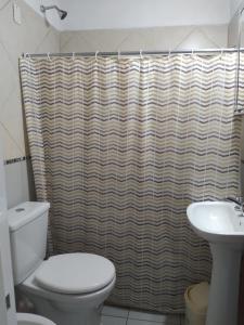 uma casa de banho com uma cortina de chuveiro e um WC e lavatório. em Las orquídeas em Goya