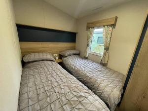 two beds in a small room with a window at Sleepy Hollow Holiday Home in Knaresborough