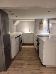 a kitchen with white cabinets and a sink and a dishwasher at Beach Walk Sandgate in Sandgate