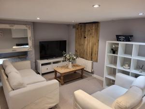 a living room with white furniture and a flat screen tv at Beach Walk Sandgate in Sandgate