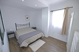 een witte slaapkamer met een bed en een raam bij 4 Mares Apartamentos C in Loredo