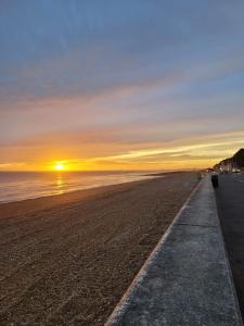 una spiaggia al tramonto con una panchina di Sea View Sandgate a Sandgate