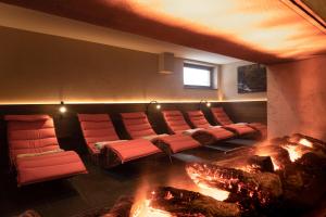a room with a fireplace with red chairs and a fire place at Aparthotel Dorfplatzl Garni in Tux