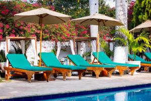 a group of chairs and umbrellas next to a pool at Entre Palmas Casa Hotel in Santa Fe de Antioquia