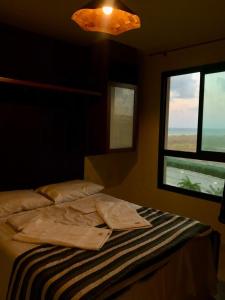 a bedroom with a bed and a window and a light at Condomínio VG sun Cumbuco in Cumbuco