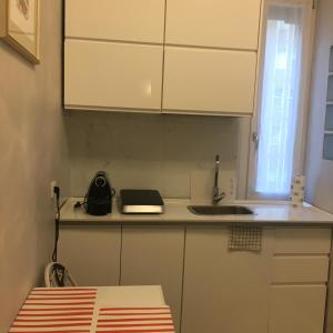 eine Küche mit weißen Schränken, einer Spüle und einer Theke in der Unterkunft Studio Monte Ceneri in Mailand