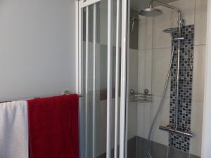 La salle de bains est pourvue d'une douche et d'une serviette rouge. dans l'établissement Au Ptit Coquelicot, à Houyet