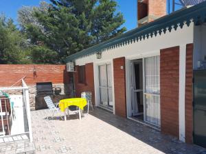 un patio con una mesa amarilla y sillas junto a un edificio en Cabaña El Hornero en Mina Clavero