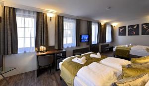 a hotel room with two beds and a tv at Herbstyle in Eger