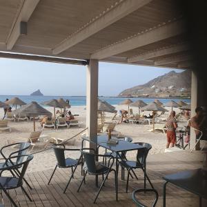 a patio with tables and chairs on the beach at Sky Mariposa sospesa sul mare in Mindelo