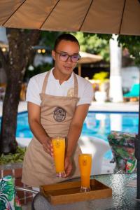 a man holding a tray with an orange juice at Entre Palmas Casa Hotel in Santa Fe de Antioquia