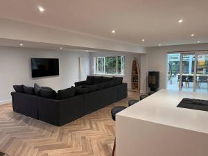 a living room with a black couch and a table at Beautiful 5 bedroom home ideal for large groups in Ryde