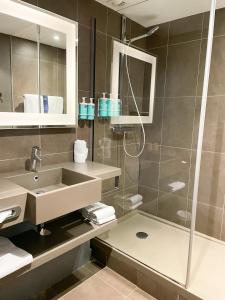 a bathroom with a sink and a shower at Novotel Fontainebleau Ury in Ury