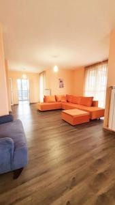 una sala de estar con sofás naranjas y suelo de madera. en Елегантен градски апартамент с обширна тераса, en Pernik