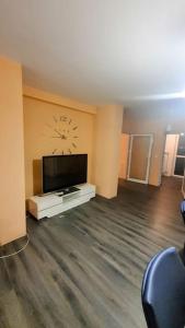 sala de estar con TV y reloj en la pared en Елегантен градски апартамент с обширна тераса, en Pernik