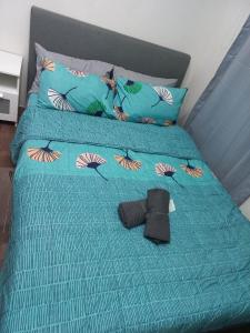 a bed with a blue comforter with a pair of shoes on it at Air Residences Condominium Deluxe in Manila