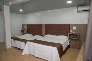 a hotel room with two beds with white sheets at Hotel Village in Garanhuns