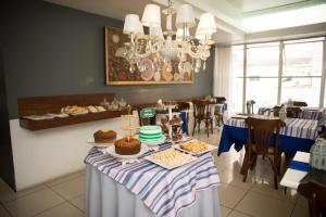 a dining room with a table with cakes and pastries at Hotel Village in Garanhuns