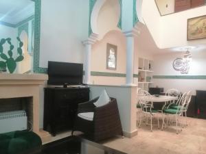 een woonkamer met een open haard en een eetkamer bij Dar Tariq 3 suites avec pisicine in Marrakesh