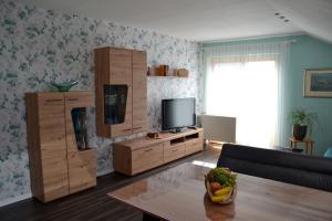 a living room with a television and a table with a bowl of fruit at Pension Anna in Bodenmais