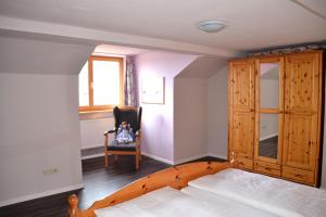 a bedroom with a bed and a chair and a window at Pension Anna in Bodenmais