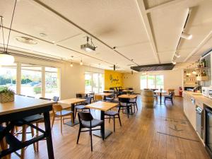 un restaurant avec des tables et des chaises dans une cafétéria dans l'établissement Kyriad Direct Roanne Hôtel, à Roanne