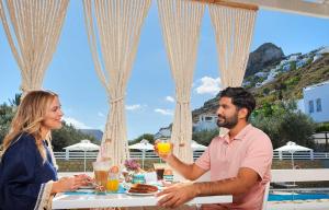 a man and woman sitting at a table drinking orange juice at Perigiali in Skiros