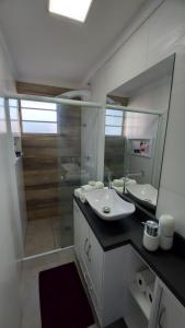 Baño blanco con lavabo y espejo en Apto Confortável próximo ao Consulado Americano, en Porto Alegre