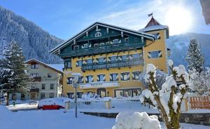 a large yellow building with snow on the ground at Posthotel Mayrhofen in Mayrhofen