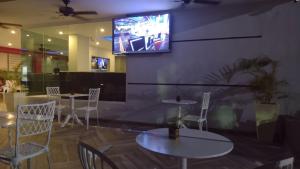 a restaurant with tables and chairs and a tv on the wall at Hotel Plaza Coral in Punta Cana