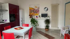 a kitchen and dining room with a white table and red chairs at Amarin Pisa Apartment in Pisa