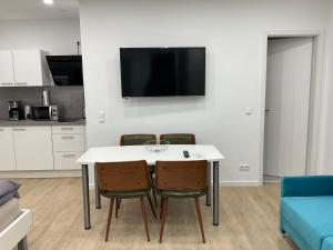 eine Küche mit einem Tisch und 2 Stühlen sowie einem TV in der Unterkunft Deluxe Apartments Messe Flughafen in Leinfelden-Echterdingen