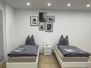 1 dormitorio con 2 camas individuales y cuadros en la pared en Deluxe Apartments Messe Flughafen, en Leinfelden-Echterdingen