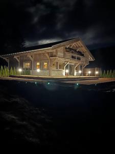 a large wooden house with lights in the night at Chalet Au Chalet de Mel très récent in La Bresse