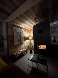 a living room with a wooden wall with a fireplace at Chalet Au Chalet de Mel très récent in La Bresse