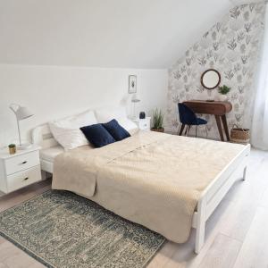 a white bedroom with a large bed and a desk at Barwy Morza in Kopalino