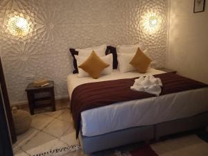 a bedroom with a large bed with brown and white pillows at Riad Beni Sidel in Marrakech